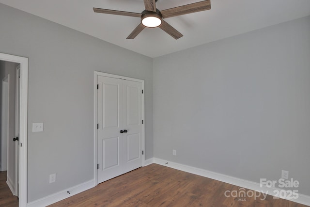 unfurnished bedroom featuring ceiling fan, baseboards, dark wood finished floors, and a closet