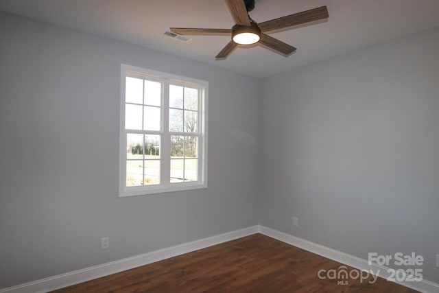 spare room with dark wood-style floors, plenty of natural light, visible vents, and baseboards