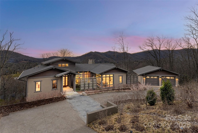 view of front of home with an outbuilding, a chimney, an attached garage, a mountain view, and driveway