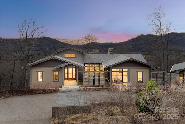 view of front of home with a chimney, fence, a mountain view, and roof with shingles