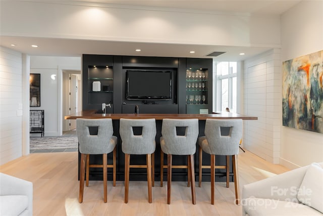 bar with light wood-type flooring, indoor wet bar, visible vents, and recessed lighting