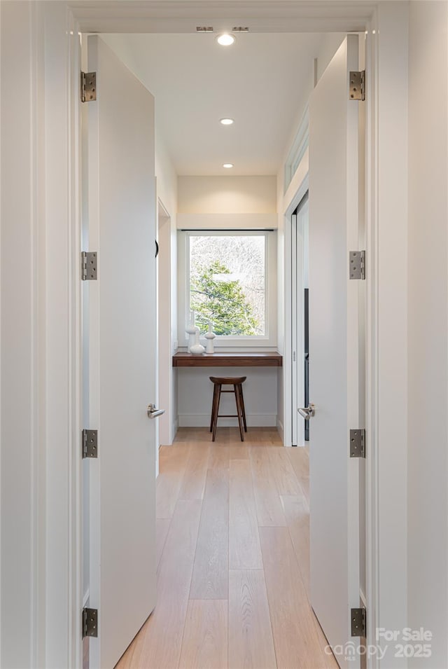 corridor featuring light wood-style flooring, baseboards, and recessed lighting