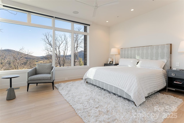 bedroom with light wood-style floors, baseboards, a mountain view, and recessed lighting