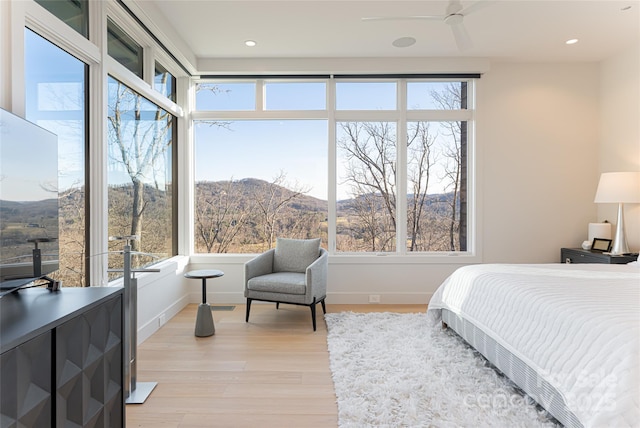 bedroom featuring light wood-type flooring, multiple windows, and baseboards