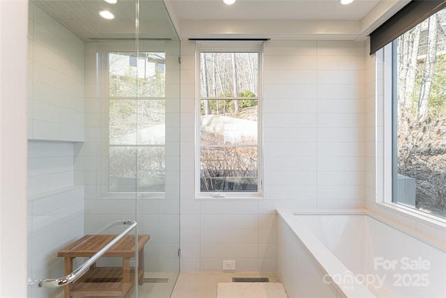 full bathroom featuring plenty of natural light, a garden tub, visible vents, and tile walls