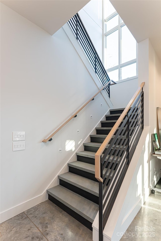 stairway featuring concrete flooring and baseboards