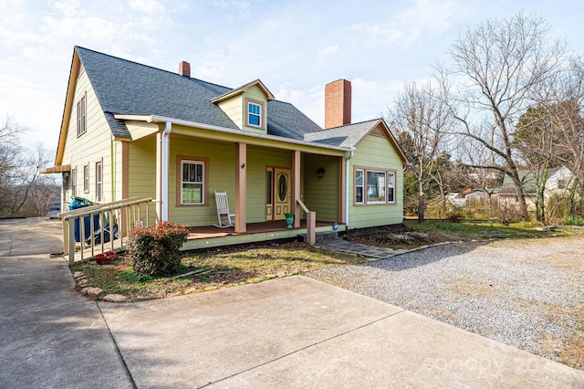 view of front of property featuring a porch, a chimney, and a shingled roof