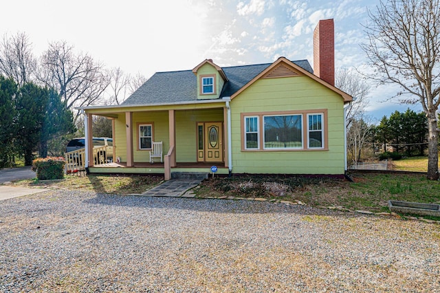 view of front of house featuring covered porch, a shingled roof, and a chimney