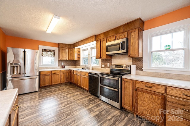 kitchen with brown cabinets, dark wood-style floors, stainless steel appliances, and light countertops