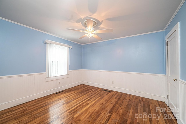 empty room with a wainscoted wall, ceiling fan, and hardwood / wood-style floors