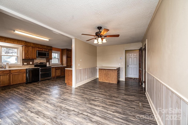 interior space with brown cabinetry, stainless steel appliances, dark wood-style flooring, and wainscoting