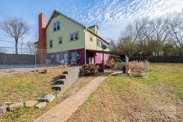 rear view of property featuring a chimney, fence, and a lawn