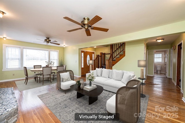 living room with wood finished floors, baseboards, and stairs