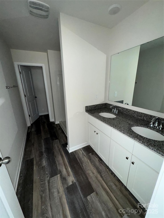 bathroom with hardwood / wood-style flooring, vanity, and a shower