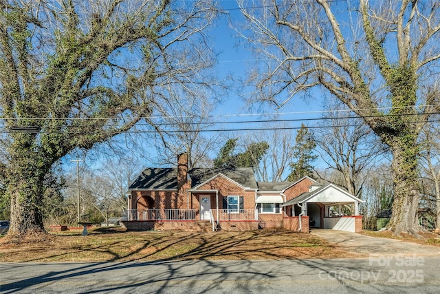 view of front facade featuring brick siding, a chimney, concrete driveway, crawl space, and an attached carport