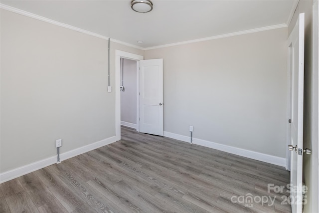 unfurnished room with ornamental molding, baseboards, and wood finished floors