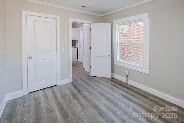 unfurnished bedroom featuring baseboards, visible vents, ornamental molding, and wood finished floors