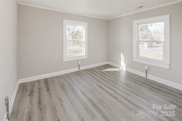 empty room featuring visible vents, baseboards, crown molding, and wood finished floors