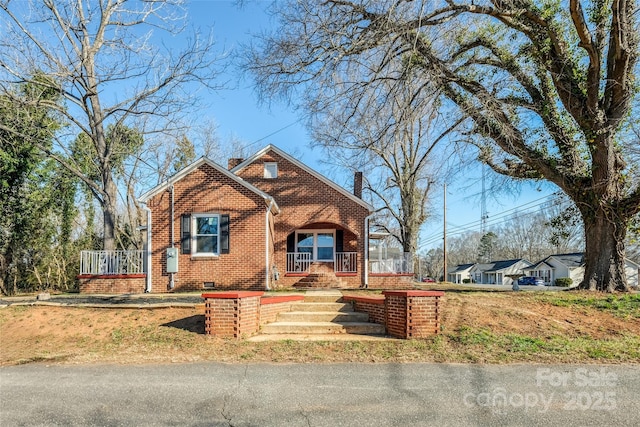 bungalow-style home featuring covered porch, brick siding, crawl space, and a chimney