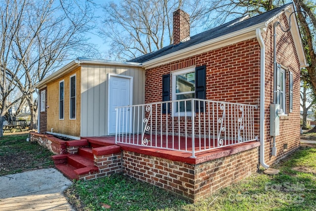 view of side of home with crawl space, brick siding, and a chimney