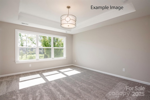 carpeted spare room featuring a tray ceiling, baseboards, and crown molding