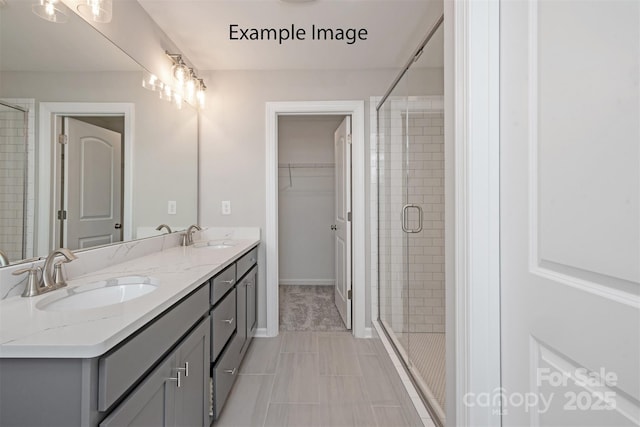 bathroom with a shower stall, double vanity, baseboards, and tile patterned flooring