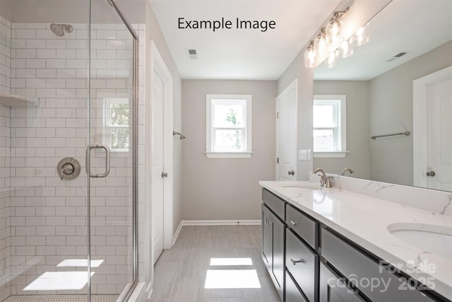 bathroom featuring baseboards, a shower stall, and double vanity