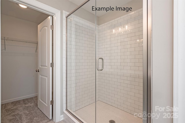 full bath with a shower stall, a spacious closet, and baseboards