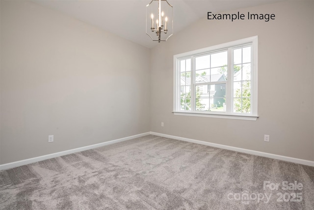 carpeted empty room featuring vaulted ceiling, a chandelier, and baseboards