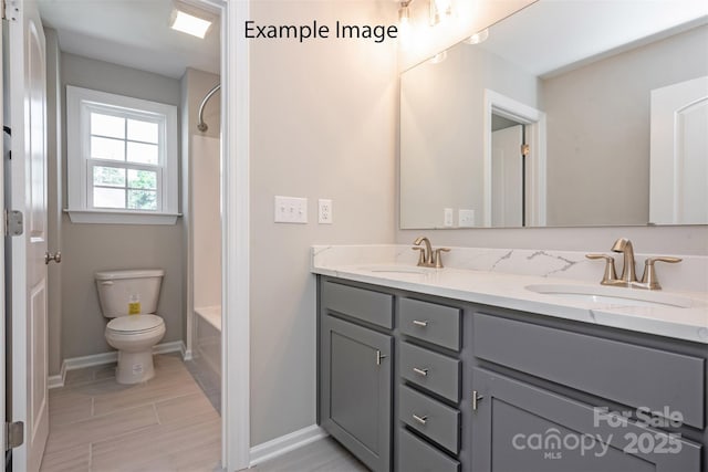 bathroom featuring toilet, baseboards, double vanity, and washtub / shower combination