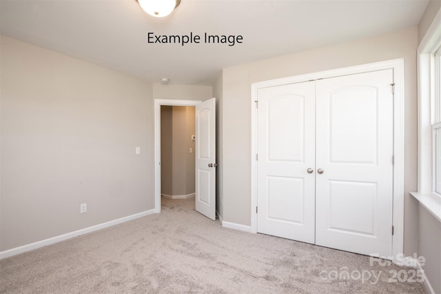 unfurnished bedroom featuring carpet flooring, baseboards, and a closet
