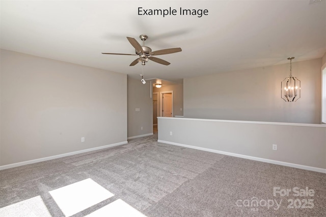 carpeted spare room featuring a ceiling fan, baseboards, and a chandelier