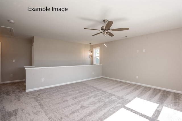 carpeted empty room featuring attic access, ceiling fan, a smoke detector, and baseboards