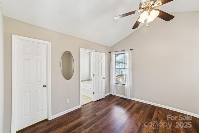 unfurnished bedroom with lofted ceiling, a ceiling fan, ensuite bath, wood finished floors, and baseboards