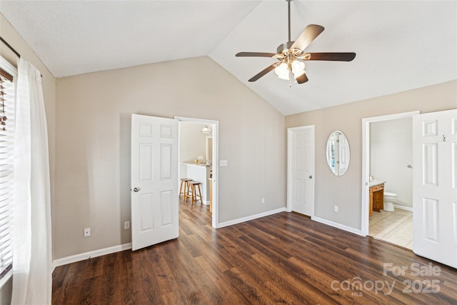 unfurnished bedroom with lofted ceiling, baseboards, and wood finished floors