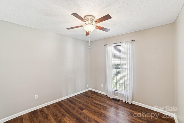 spare room featuring visible vents, baseboards, dark wood finished floors, and a textured ceiling