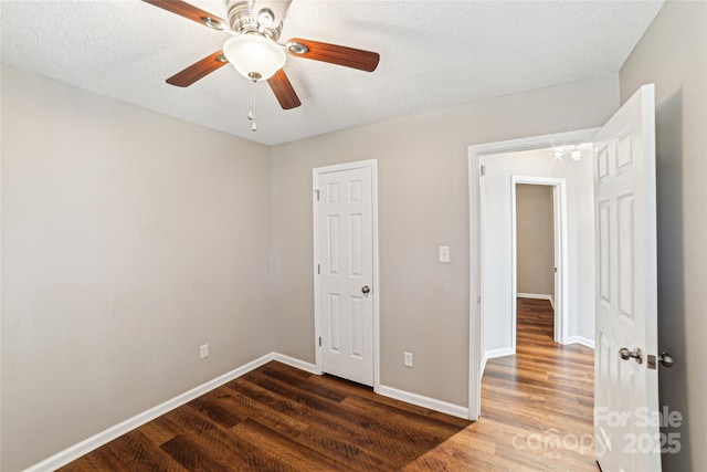 unfurnished bedroom featuring dark wood-type flooring, a textured ceiling, and baseboards