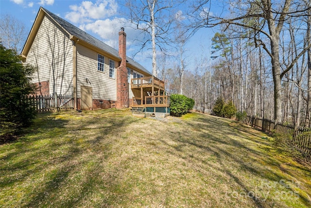 back of house featuring a chimney, a yard, a deck, and fence