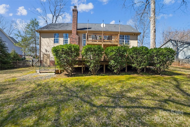 back of property with a chimney, fence, a lawn, and a wooden deck