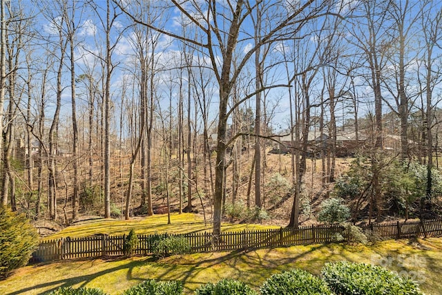 surrounding community with a forest view, fence, and a lawn