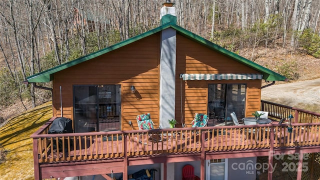 back of house featuring a chimney and a deck