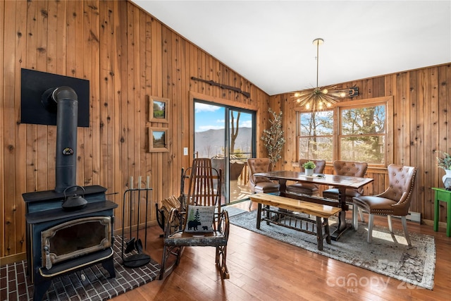 dining area with a wood stove, a healthy amount of sunlight, vaulted ceiling, and wood finished floors