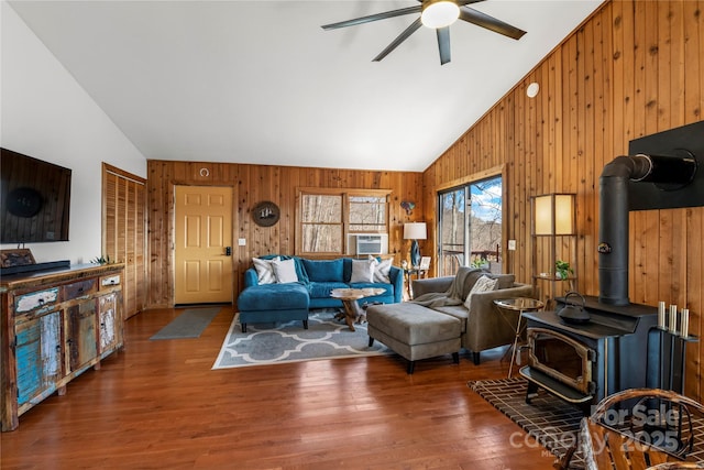 living room with a wood stove, wooden walls, high vaulted ceiling, and wood finished floors