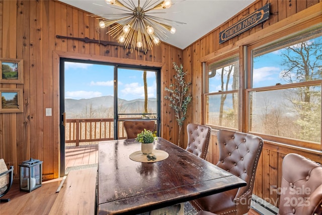 dining area with a healthy amount of sunlight, wooden walls, a mountain view, and a notable chandelier