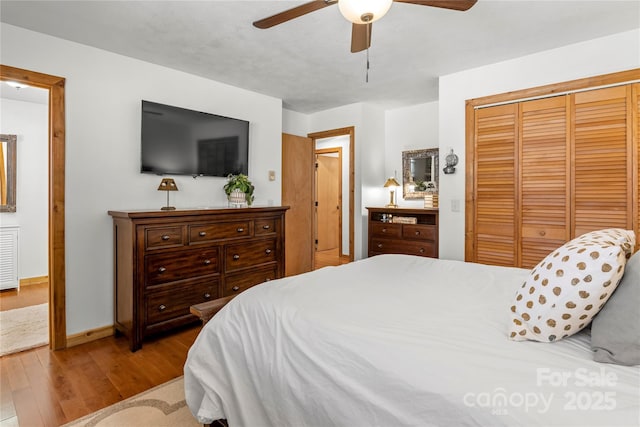 bedroom featuring a closet, ceiling fan, baseboards, and wood finished floors