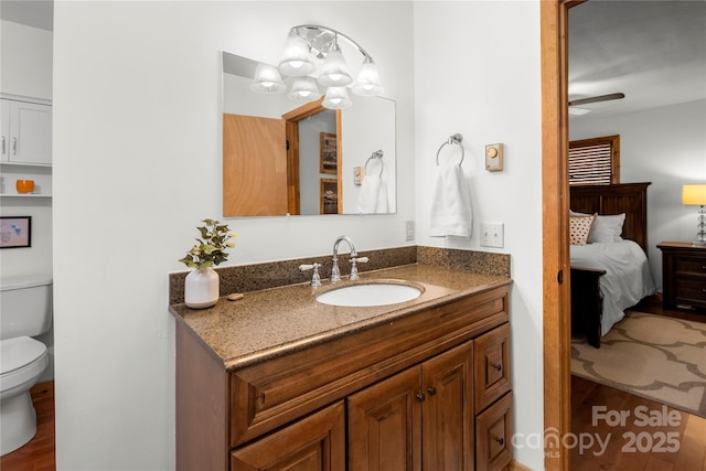 ensuite bathroom with ensuite bathroom, ceiling fan with notable chandelier, vanity, and toilet