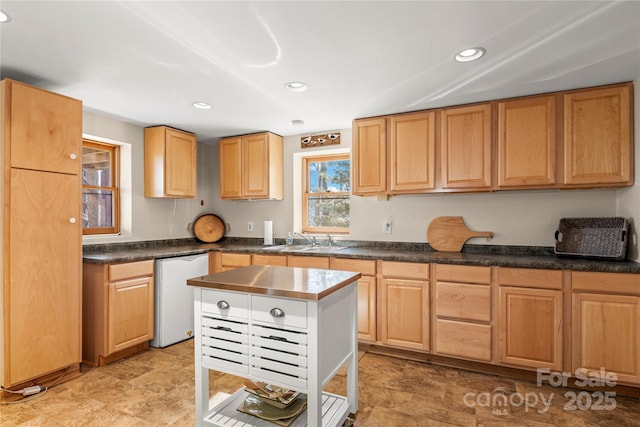 kitchen featuring recessed lighting, dishwasher, dark countertops, and a sink