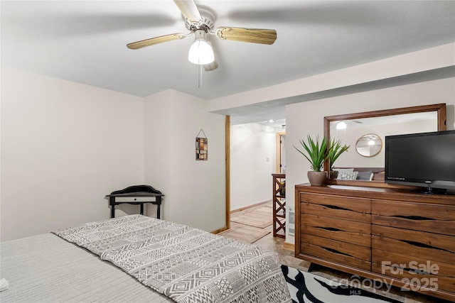 bedroom with ceiling fan, baseboards, and wood finished floors