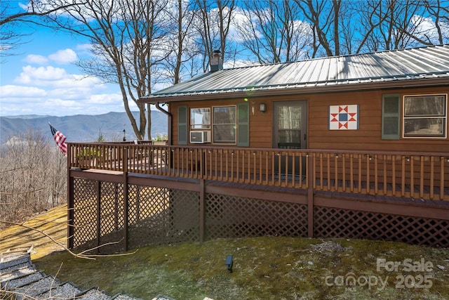 exterior space with a chimney, metal roof, and a deck with mountain view