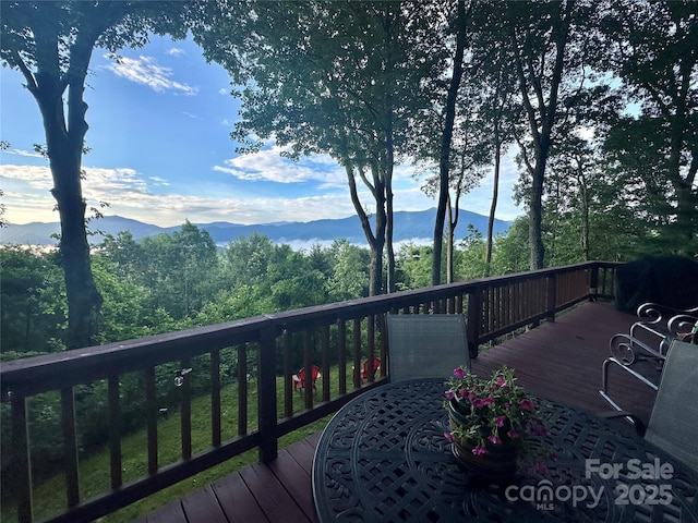 deck with outdoor dining space, a grill, and a mountain view